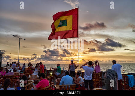 waving flag of Cartagena at sunset at Cafe del Mar Stock Photo