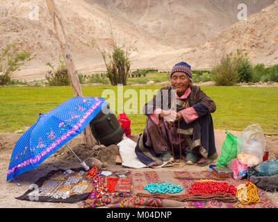 aA Buddhist old-age rural woman peddler shows her merchandise in the market Stock Photo