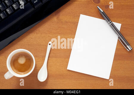 A blank sheet of paper on a desktop with a pen, a black computer keyboard and a coffee cup Stock Photo