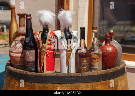 bottles of wine and alcoholic beverages standing on the old barrels on the yard landscape orientation Georgia Stock Photo