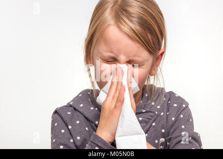 A girl is biting into a white handkerchief. She is 7 years old and wears a gray white dotted pullover Stock Photo