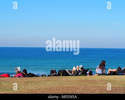 group of friends lying in the sun and relaxing having fun  at the promenade near the beach in front of the sea on a perfect day with clear blue sky Stock Photo