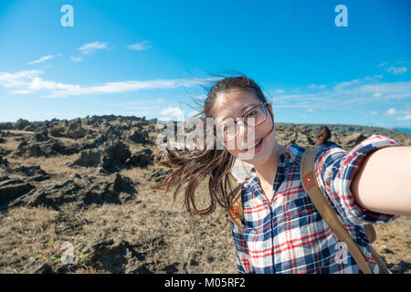 happy elegant woman tourist going to island country travel during summer vacation and taking picture selfie with rock stone landscape. Stock Photo