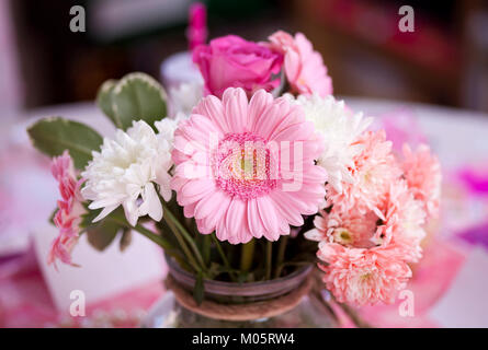 A bunch of beautiful pink and white flowers including gerberas and roses in a vase on a table Stock Photo