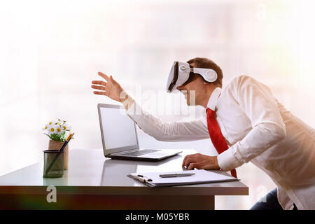 Surprised businessman wanting to touch virtual image on his office desk. Horizontal composition. Stock Photo