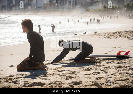 RIO DE JANEIRO - MARCH 20, 2017: Surfers stretch on the beach before heading into the waves at the surf break at Arpoador. Stock Photo