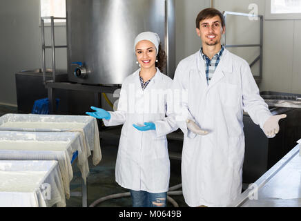 Two smiling workers in lab coats showing their production process at  dairy production Stock Photo
