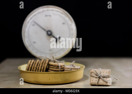 Samoyed cakes tied in bundles and kitchen scale. Cookies on a wooden kitchen table. Black background. Stock Photo