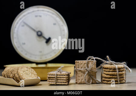 Samoyed cakes tied in bundles and kitchen scale. Cookies on a wooden kitchen table. Black background. Stock Photo