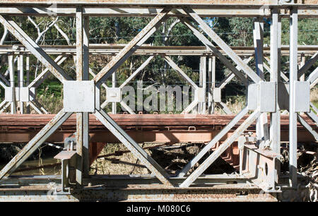 Abstract view of an old disused and partially dismantled bridge constructed with heavy duty metal frame that is now rusting. Stock Photo