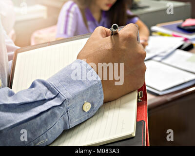 Close up shot businessman writing notes in notebook Stock Photo