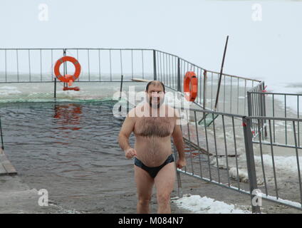 Epiphany in Russia. Male wanting to imitate Jesus Christ, three times, dipped in ice-cold Holy water and leaving the water shines with happiness. Stock Photo