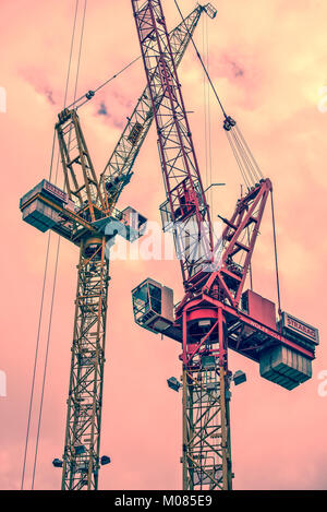 Two building cranes in front of red skyconstruction zone 	 Two building cranes in front of red sky Stock Photo