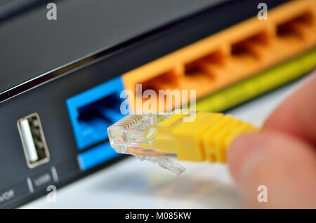 Details of hand plugging in internet modem cables Stock Photo