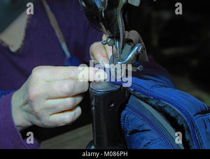 In the Shoe shop of female hands sew the lock on the boots on the sewing machine Stock Photo