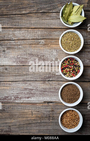 Herbs and spices in white bowls on an old wooden table Stock Photo