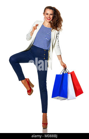 Luxury Shopping. The French way. Full length portrait of cheerful stylish woman in white jacket isolated on white background with shopping bags painte Stock Photo
