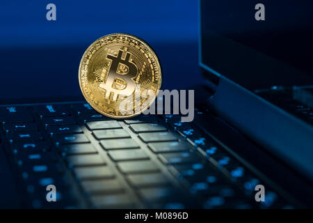 Bitcoin coin standing on keyboard of computer Stock Photo