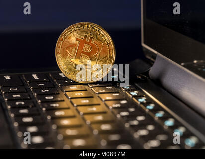 Bitcoin coin standing on keyboard of computer Stock Photo