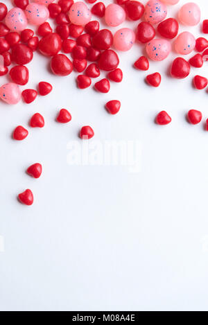 Red cinnamon hearts with red and pink jelly beans on white background portrait format Stock Photo