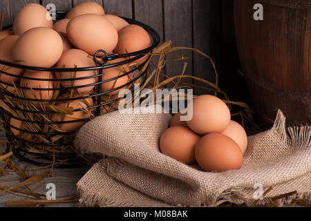 Brown chicken eggs in a basket and on a burlap cloth Stock Photo