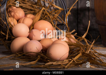 Closeup of brown chicken eggs spilled from a basket onto a wooden surface Stock Photo