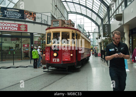 Historic tram outside the booking office/ terminus New Regent Street, inside the shopping centre, with shoppers and young man texting. Stock Photo