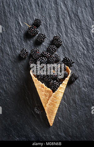 Blackberry explosion. Photo of blackberry in waffle cone on black slate. Top view. High resolution product. Stock Photo