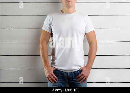 Young man in a white T-shirt on a light wooden background. Mockup  clothes Stock Photo