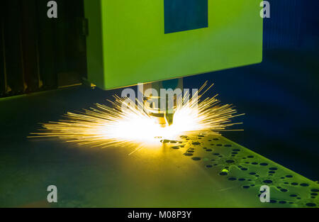 CNC machine laser cutting process metal sheet with sparking. Stock Photo