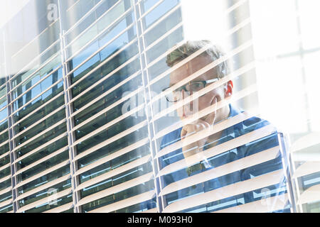 Casual businessman working in office, sitting at desk, typing on keyboard, looking at computer screen. Stock Photo