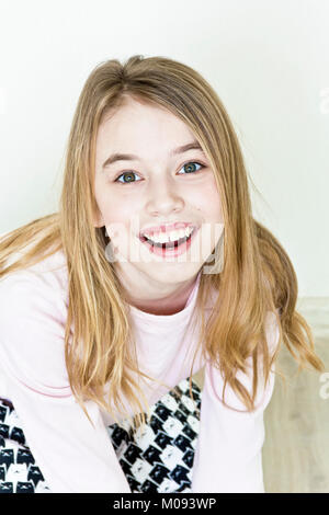 Laughing cute girl eleven years old are sitting on floor Stock Photo