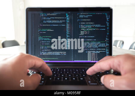 Programmer profession - man writing programming code on laptop computer. Stock Photo