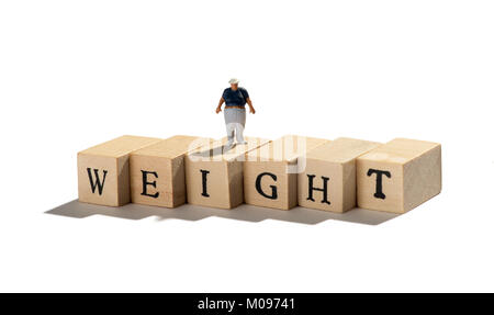 Weight concept with an overweight obese miniature fat boy figure standing on a row of wooden blocks spelling the word over white with copy space Stock Photo