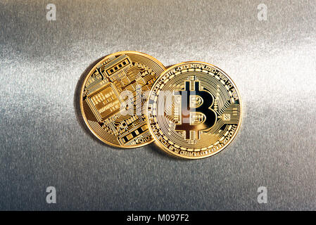 Two gold Bitcoins on a reflective metallic silver background with copy space in a concept of virtual cryptocurrencies, finances and investment Stock Photo