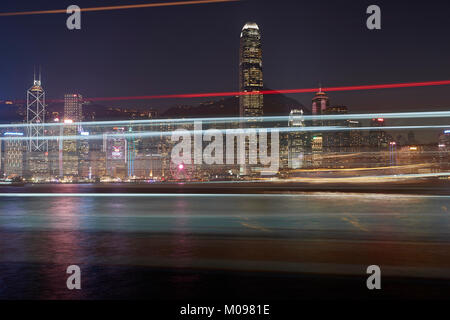 Light Trails From A Passing Ferry And Hong Kong Central District And Victoria Harbour At Sunset. Stock Photo