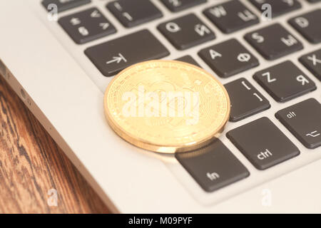 Crypto currency bitcoin coin  on computer keyboard on wooden Stock Photo