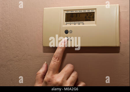 woman hand regulating an home thermostat Stock Photo