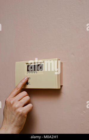 woman hand regulating an home thermostat Stock Photo