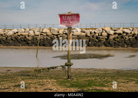 Sign: Beware soft mud, seen in Herne Bay, Kent, England, UK - with Neptunes Arm in the background Stock Photo