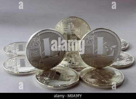 On a white background are silver coins of a digital crypto  currencies - Litecoin and Bitcoin. In addition to the lying coin, there are one standing b Stock Photo