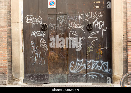 Graffiti sprayed in white paint on an old wooden door in Bologna Italy Stock Photo