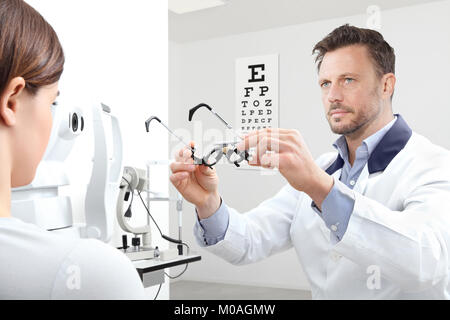 optometrist with trial frame examining eyesight  woman patient in optician office