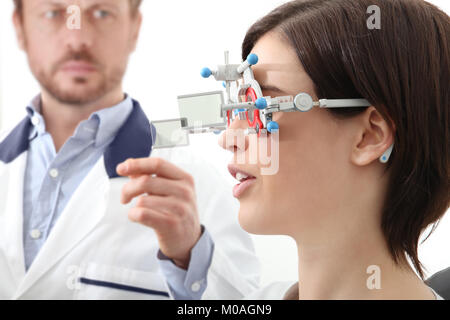 optometrist with trial frame examining eyesight  woman patient in optician office