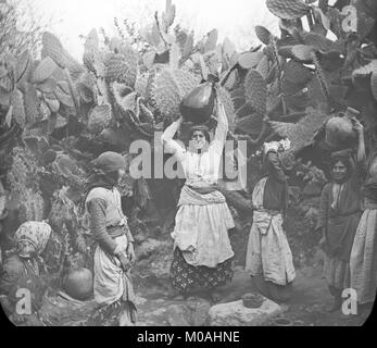 Late 19th or early 20th century black and white photograph showing a group of women at the Well Of Cana in Israel. The women are collecting water in large water jugs, and carrying them back on their heads. Stock Photo