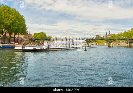 PARIS, FRANCE - MAY 15, 2017: Touristic boat passes below Pont des Arts on Seine river in Paris. Paris is the top touristic destination in Europe. Stock Photo