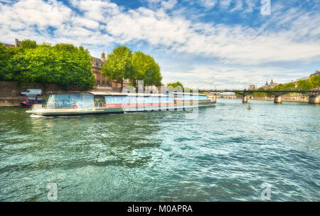 Touristic boat passes below Pont des Arts on Seine river in Paris. Paris is the top touristic destination in Europe. Stock Photo