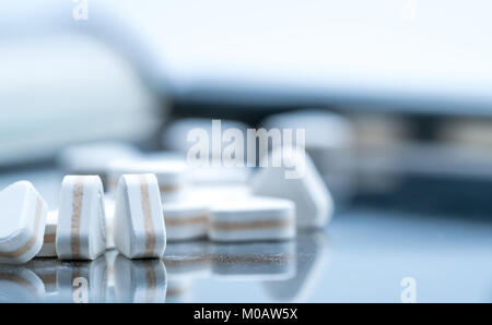 Macro shot of triangle shape tablet pills. Three layers tablet pills for indication antacid, digestive and gastric pain. Group of sandwich tablets pil Stock Photo