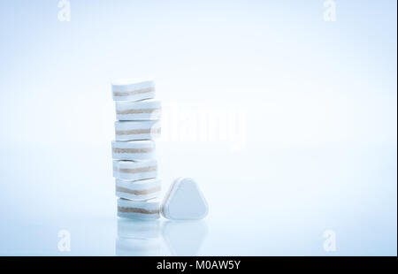 Macro shot of triangle shape tablet pills. Three layers tablet pills for indication antacid, digestive and gastric pain. Group of sandwich tablets pil Stock Photo