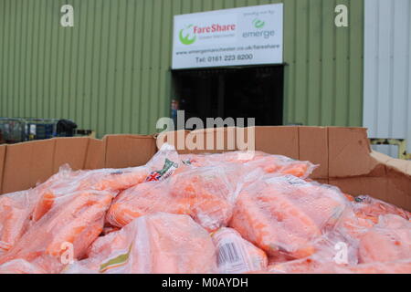 Carrots in plastic bags in a large box in front of FareShare Greater Manchester depot, where they fight food waste and food poverty Stock Photo